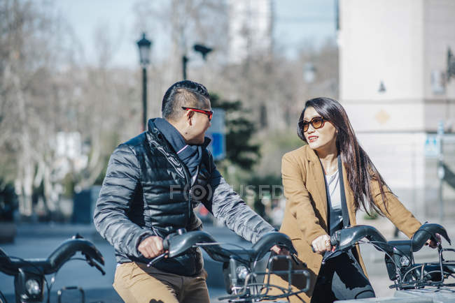 Chinese couple in Madrid riding bicycles, Spain — Stock Photo