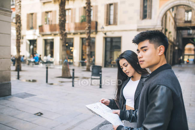 Junges paar schaut auf eine karte in barcelona, spanien — Stockfoto