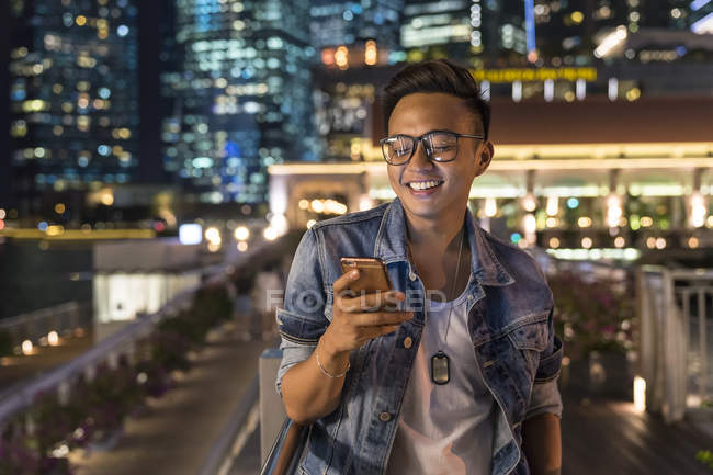 Giovane uomo giocare con il suo smartphone in città — Foto stock