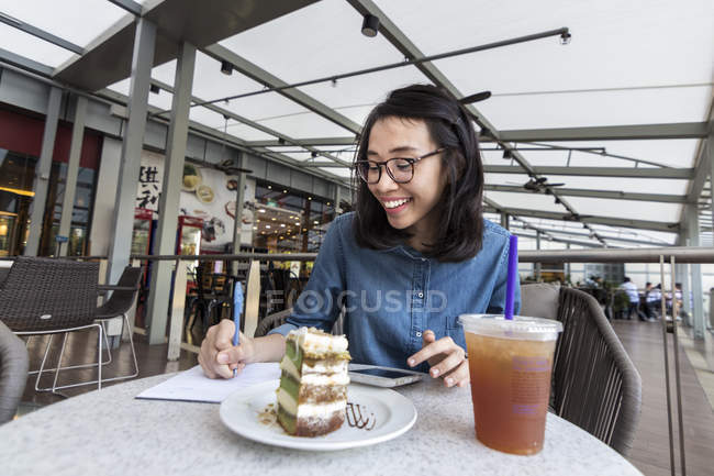 Junge Frau notiert in einem Café ein paar Informationen. — Stockfoto