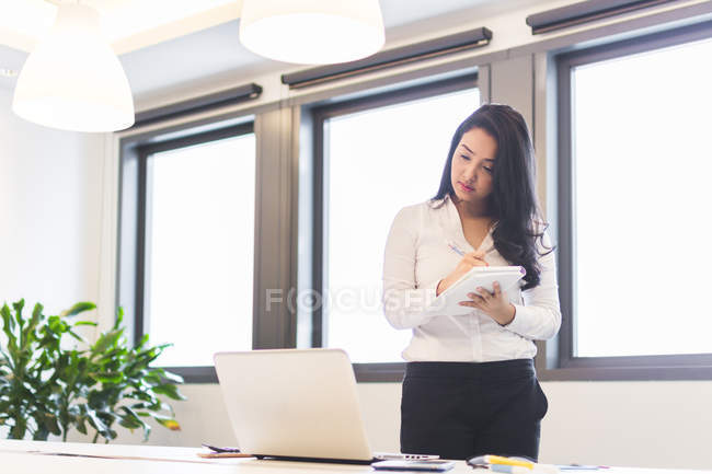 Jeune femme Jotting notes dans le bureau moderne — Photo de stock