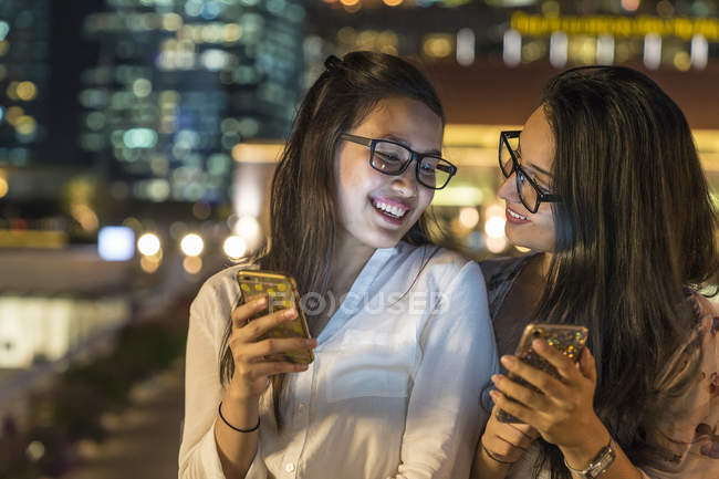 Deux jeunes femmes avec leurs smartphones dans la ville urbaine — Photo de stock