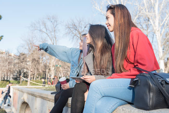 Philippine friends women enjoying with tablet in Retiro Park Madrid next to the lake, Spain — Stock Photo