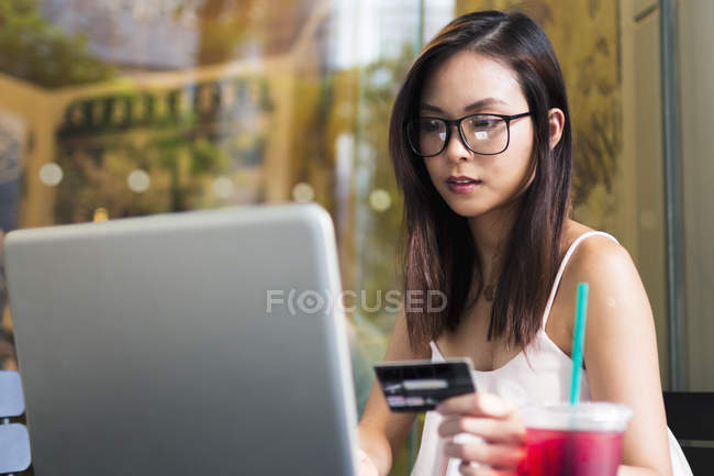 Bella asiatico ragazza fare un transazione su il suo computer portatile . — Foto stock
