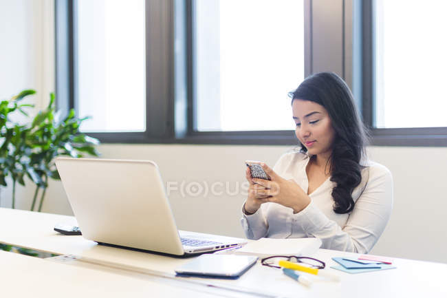 Молодая женщина работает с телефоном в современном офисе — стоковое фото