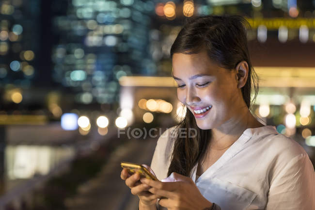 Молодая красивая азиатская женщина с помощью смартфона на открытом воздухе — стоковое фото