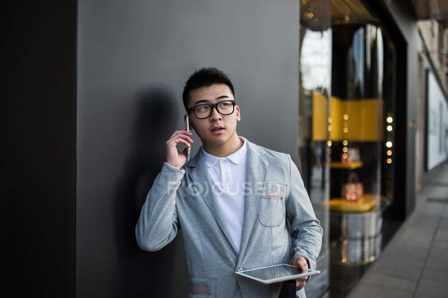 Uomo d'affari cinese che parla al telefono per strada accanto a un negozio di lusso in Serrano Street, Madrid, Spagna — Foto stock