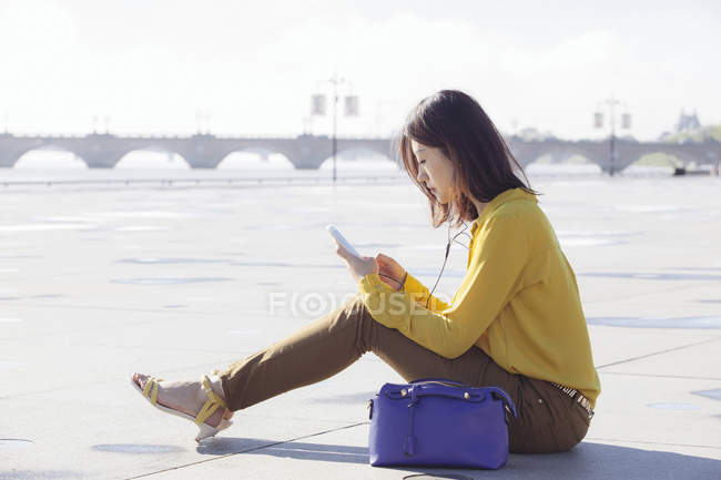 Vista lateral de la mujer joven navegando por su teléfono - foto de stock