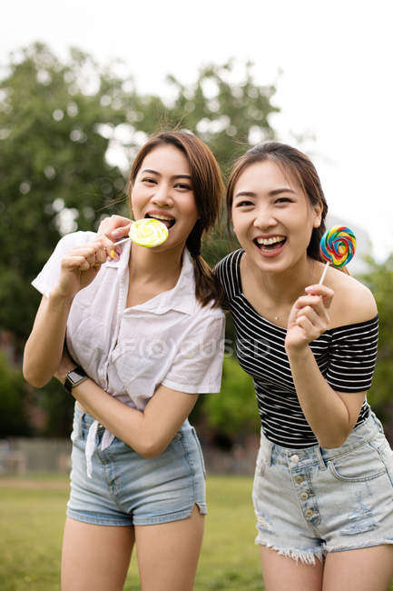 Adolescents asiatiques copines avec des bonbons s'amuser dans le parc — Photo de stock