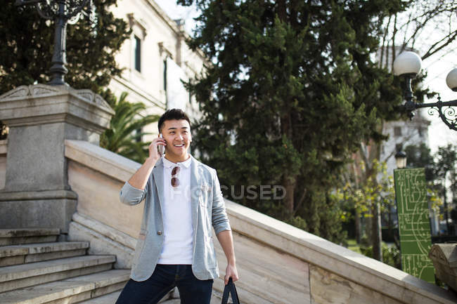 Homme d'affaires chinois joyeux parlant au téléphone dans la rue, Espagne — Photo de stock
