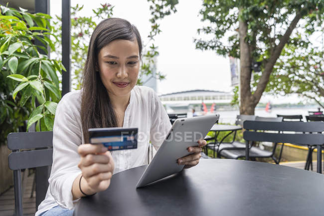 Young beautiful asian woman making transaction with tablet — Stock Photo