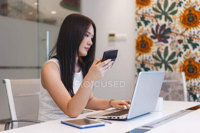 Mujer joven sosteniendo una taza de café en la oficina moderna - foto de stock