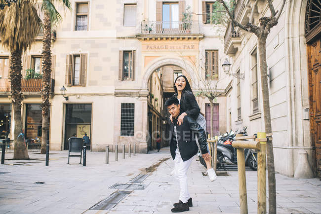 Junges paar spielt huckepack in der mitte von barcelona, spanien — Stockfoto