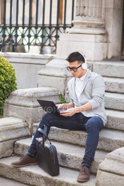 Hombre de negocios chino que trabaja al aire libre utilizando una tableta, España - foto de stock