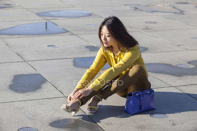 Chinese woman putting on her shoes outdoors — Stock Photo