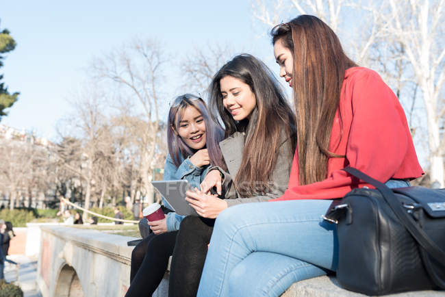 Філіппінські друзі жінок, спільний доступ до екрану електронні таблетку в Мадриді парку Ретіро біля озера, Іспанія — стокове фото