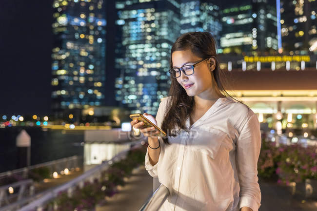 Young beautiful asian woman using smartphone outdoors — Stock Photo