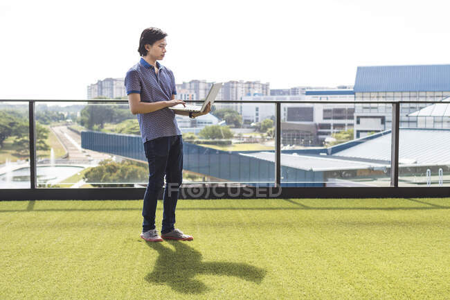 A young man standing with laptop — Stock Photo