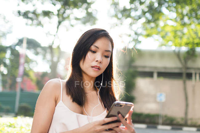 Прелестная азиатская девушка с телефоном на улице — стоковое фото