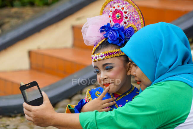 Une fille et sa mère prennent une photo ensemble avant de rejoindre un festival de danse à Jakarta. — Photo de stock