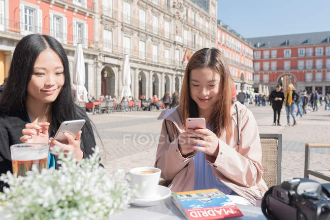 Asiatische Frauen in einem Café mit Smartphones in Madrid, Spanien — Stockfoto