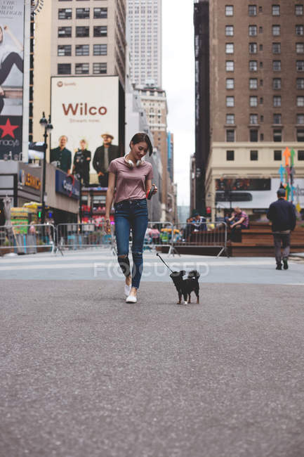 Belle femme promenant ses chiens à travers la ville avec l'état empire derrière
. — Photo de stock