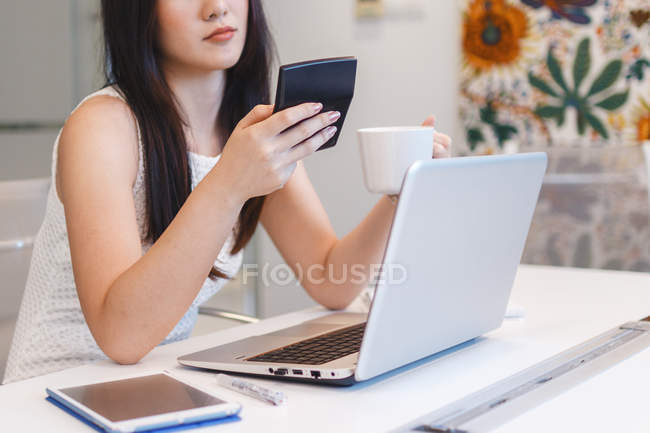 Junge Frau arbeitet mit Taschenrechner in modernem Büro — Stockfoto