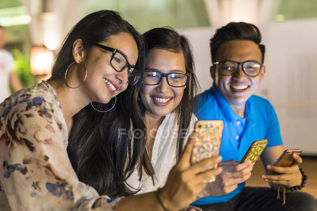 Un grupo de amigos jugando con sus teléfonos inteligentes . - foto de stock