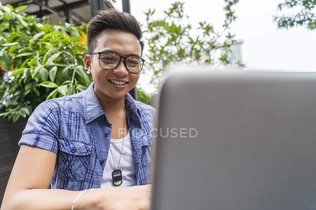 Ein philippinischer mann bei der arbeit an seinem laptop. — Stockfoto