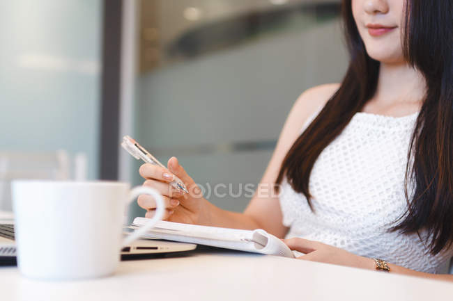 Jovem mulher tomando notas no escritório moderno — Fotografia de Stock