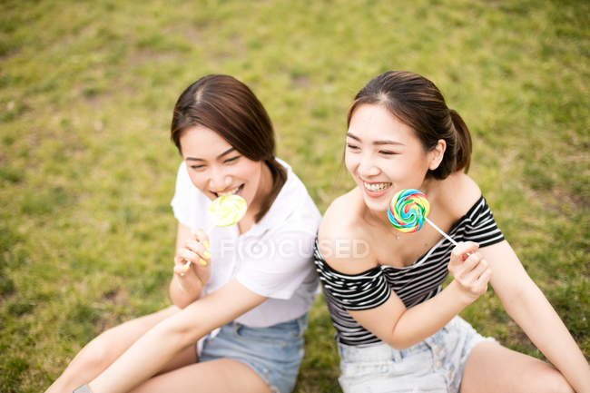 Adolescentes asiáticos novias con caramelos divertirse en el parque - foto de stock