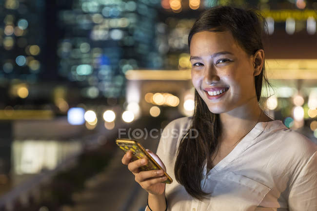 Молодая красивая азиатская женщина с помощью смартфона на открытом воздухе — стоковое фото