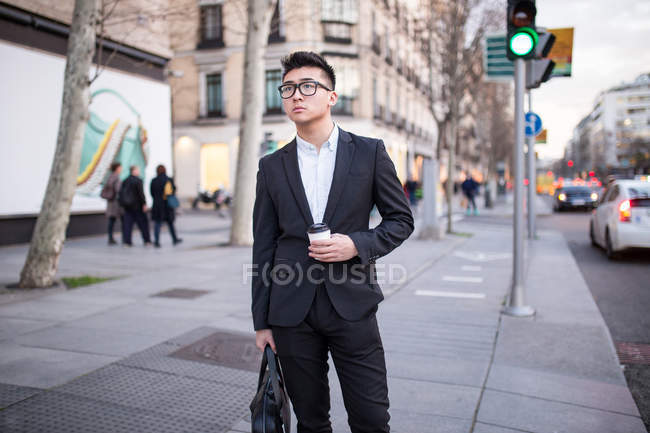 Empresário chinês de pé ao ar livre segurando uma xícara de café, Espanha — Fotografia de Stock
