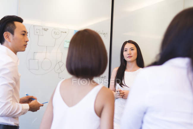 Mujer joven haciendo la presentación a sus colegas en la oficina moderna - foto de stock