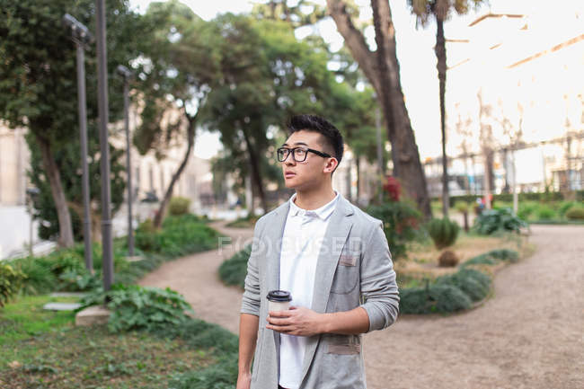 Uomo d'affari cinese in piedi all'aperto con una tazza di caffè, Spagna — Foto stock