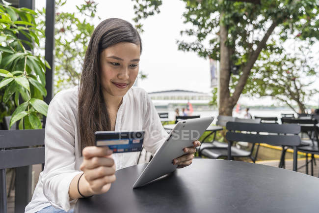 Jovem bela mulher asiática fazendo transação com tablet — Fotografia de Stock