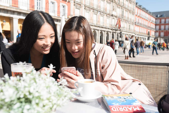 Mulheres asiáticas em um café usando smartphone em Madrid, Espanha — Fotografia de Stock