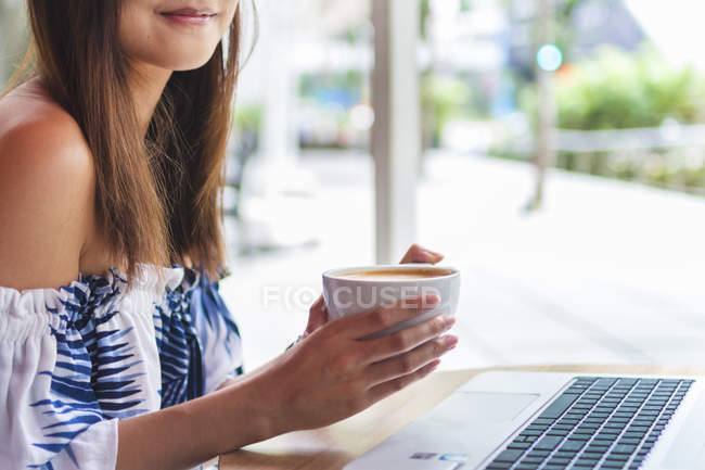 Joven mujer china sosteniendo una taza de café - foto de stock