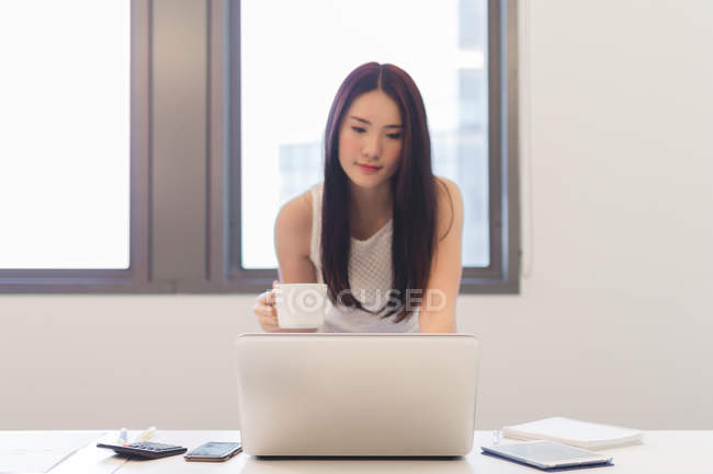 Jovem mulher trabalhando com seu laptop no escritório moderno — Fotografia de Stock
