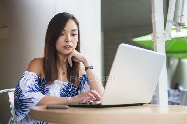 Jovem mulher chinesa ocupada trabalhando em seu laptop — Fotografia de Stock