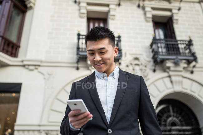 Empresario chino mensajeando por teléfono en la calle en Madrid, España - foto de stock