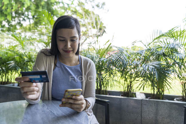 Giovane attraente asiatico donna making transazione con smartphone — Foto stock
