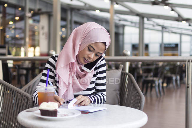 Jovem mulher anotando algumas informações em um café — Fotografia de Stock
