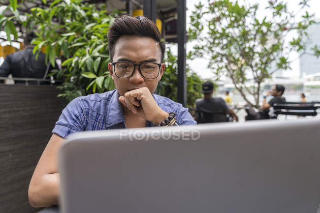Ein philippinischer mann arbeitet an seinem laptop im cafe — Stockfoto
