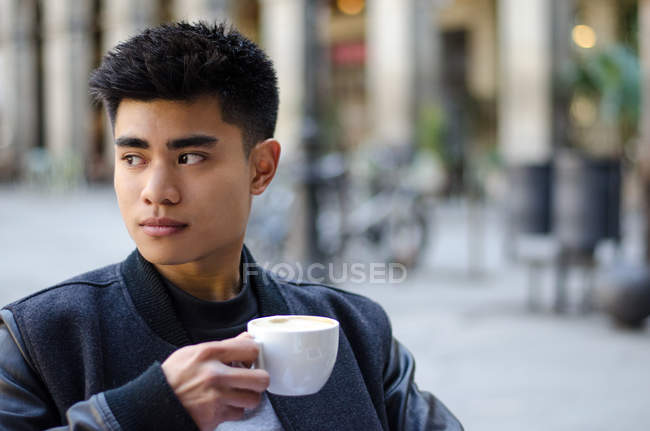 Portrait of a young asian man having a coffee in Barcelona, spain — Stock Photo