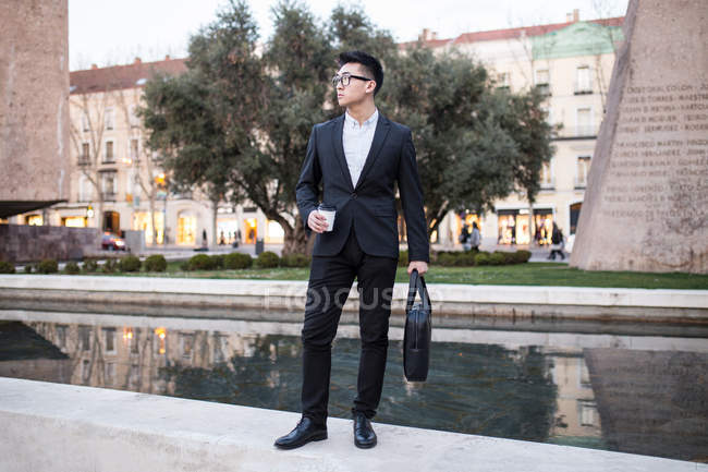 Китайський бізнесмен, стоячи на відкритому повітрі тримаючись за чашкою кави, Іспанія — стокове фото