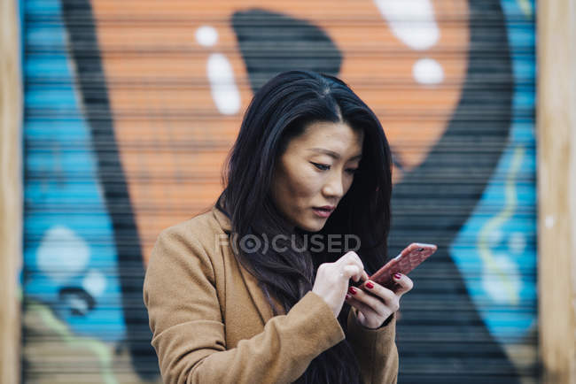Chinesin checkt ihr Handy in Madrid und schaut auf Handy, Spanien — Stockfoto
