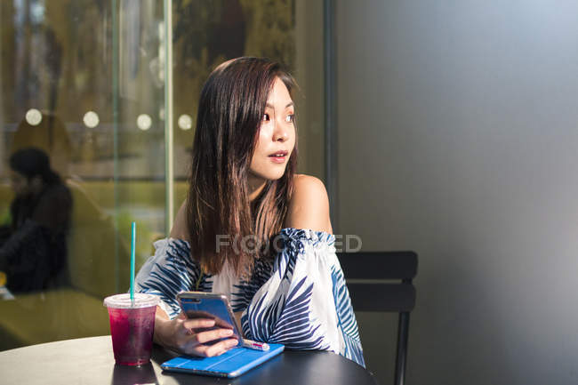 Menina asiática bonita com um telefone no café — Fotografia de Stock