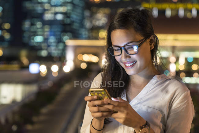 Молода красива азіатська жінка використовує смартфон на відкритому повітрі — стокове фото