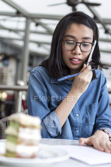 Young Woman Jotting Down Some Information At A Cafe. — Stock Photo